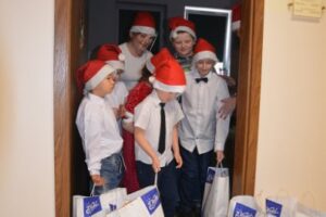 Zdjęcie przedstawia wychowanków, którzy otrzymali paczki od Mikołaja. Wychodzą na korytarz z sali - paczki czekają na korytarzu.