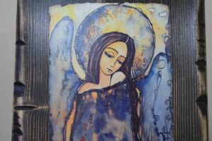 Na zdjęciu widocznych jest obraz anioła, ręcznie malowany na drewnie.