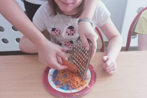 Na zdjęciu wychowanka i opiekun trą marchewkę
