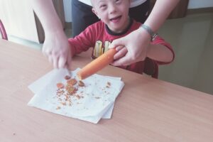 Na zdjęciu wychowanek i opiekun trą marchewkę