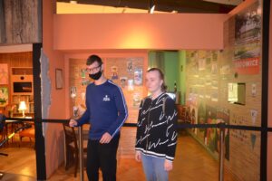 Na zdjęciu widocznych jest 2 osoby. Znajdują się w Muzeum Śląskim w Katowicach. Stoją obok jednej z muzealnych ekspozycji.