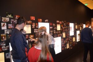 Na zdjęciu znajdują się 4 osoby. Przebywają w jednym z pomieszczeń Muzeum Śląskiego w Katowicach. 3 osoby oglądają muzealną ekspozycję stworzoną ze zdjęć.