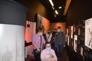 Na zdjęciu znajduje się 8 osób. Znajdują się w Muzeum Śląskim w Katowicach. Idą jednym z korytarzy. Oglądają muzealną ekspozycję stworzoną z plakatów, zdjęć i tekstów.