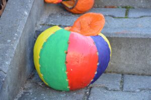 Na zdjęciu widoczna jest dynia. Dynia została pomalowana farbami i przypomina piłkę.