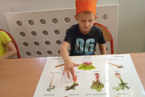 Na zdjęciu wychowanek pokazuje na planszy marchewkę