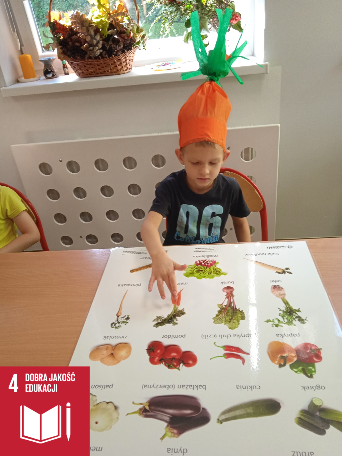 Na zdjęciu wychowanek pokazuje na planszy marchewkę