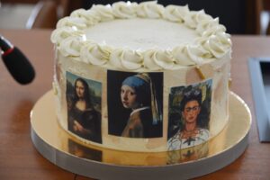 Na zdjęciu widoczny jest tort. Na torcie umieszczone zostały obrazy znanych malarzy: Mona Lisa Leonarda da Vinci, Dziewczyna z perłą Jana Vermeera,