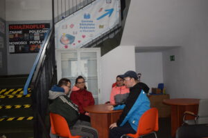 Na zdjęciu uczestnicy WTZ siedzą przy stoliku w budynku biblioteki w Kluczach.