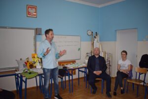 Na zdjęciu znajdują sie 3 osoby. Od lewej Sebastian Sierka - kierownik WTZ, stoi i przemawia, następnie Daniel Malinowski - dyrektor ZSP w Łobzowie, uczestniczka spotkania.